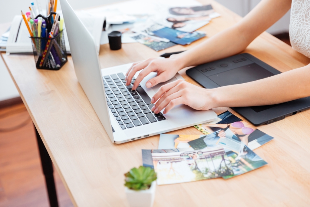Woman photograper typing on laptop keyboard and using graphic tablet